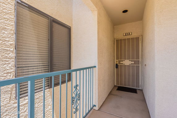 Exterior entrance of an apartment with a security door and adjacent window.