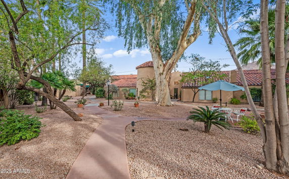 Front view of a house with red tile roof and trees in the foreground.