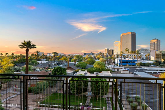 Panoramic view of a cityscape with tall buildings and palm trees at sunset.
