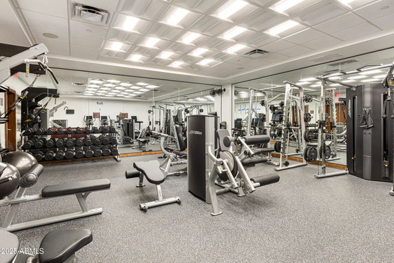 Interior view of a gym with various fitness equipment and mirrored walls.