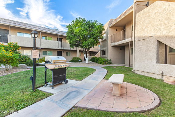 Front view of a two-story apartment building with exterior walkways and a central seating area.