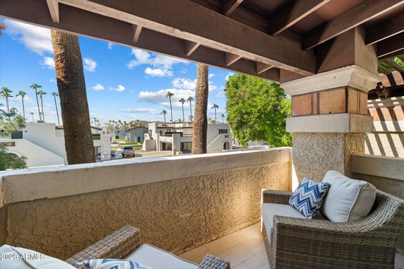 Balcony view showing rooftops and palm trees in a residential area.