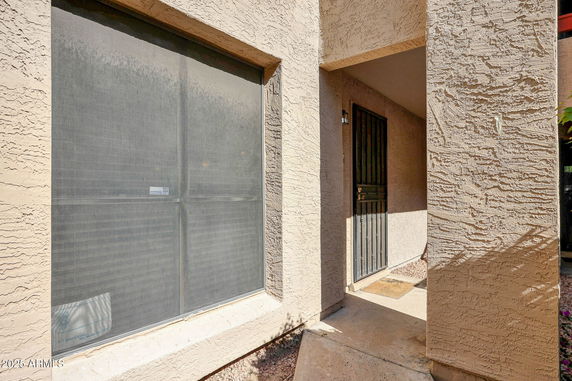 Exterior corner view of a building showing a textured wall and a metal door.