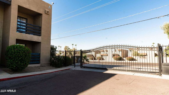 Front view of a multi-story building with balconies and gated entrance.