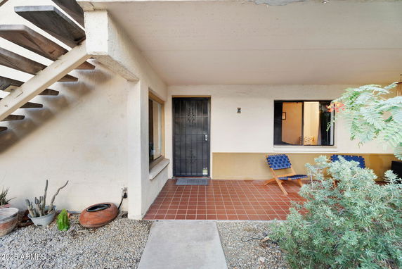 Front view of a building entrance with a tiled patio and staircase.