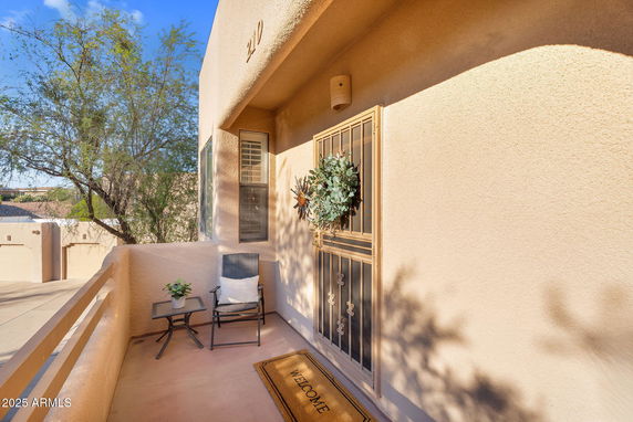 Front view of a beige stucco house exterior with a decorative door and small patio area.