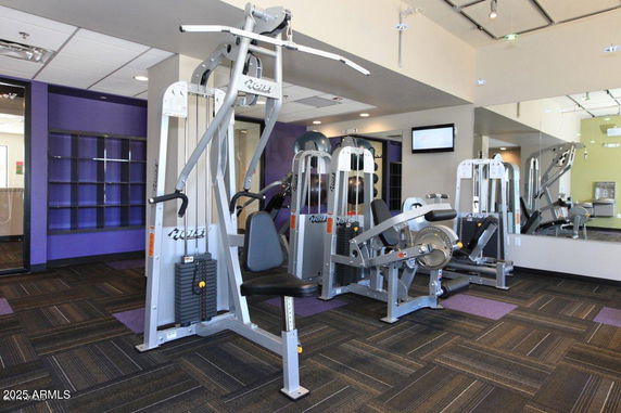 Interior view of a modern gym with exercise machines and mirrored walls.