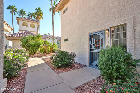 Front view of a house with decorative metal screen door and desert landscaping.