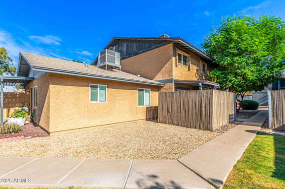 Front view of a multi-story house with a fence and gravel yard.
