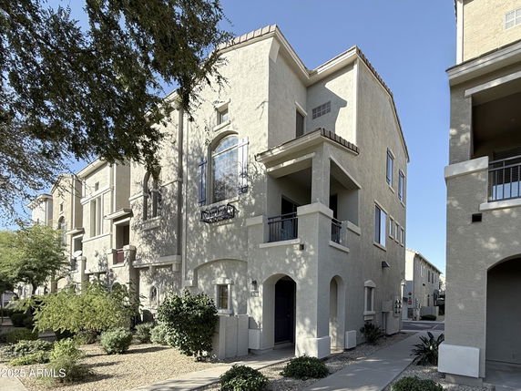 Front view of a multi-story residential building with balconies and arched windows.