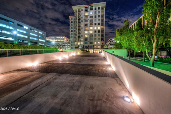 Front view of a tall residential building at night with lights along the entrance pathway.