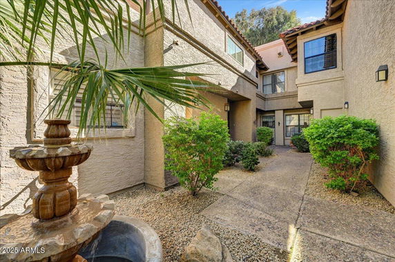 Front view of a residential building with textured walls and a fountain in the courtyard.