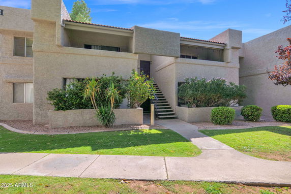 Front view of a two-story building with textured walls and external staircase.