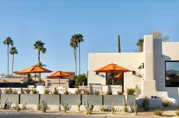 Front view of a modern house with white stucco walls and patio umbrellas.