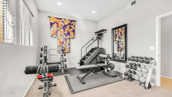 Indoor gym area with exercise equipment and weights.