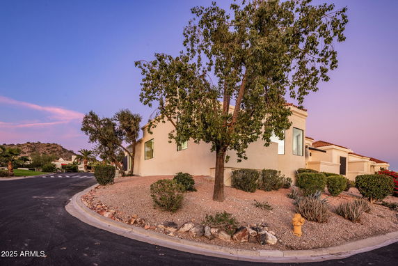 Front view of a stucco house with a flat roof and desert landscaping.