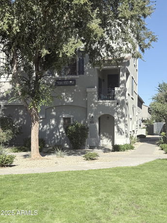 Front view of a multi-story residential building with arched entryway and balcony.