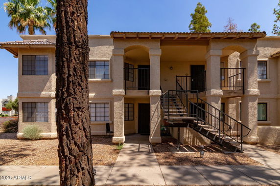 Front view of a two-story building with exterior staircase and columns.