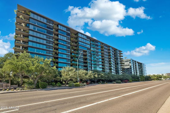 Front view of a multi-story modern building with glass facade and balconies.