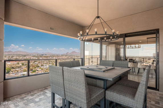 Panoramic view from a modern balcony overlooking a cityscape and distant mountains.