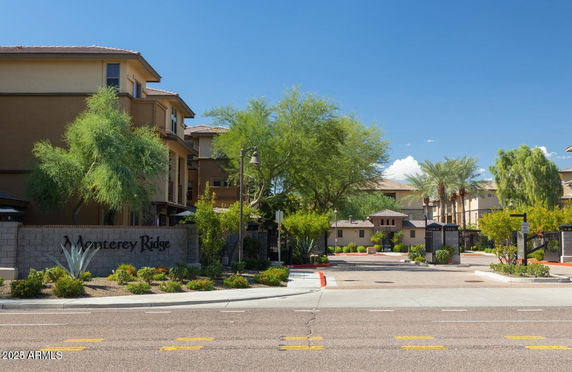 Front view of a three-story residential building complex with lush landscaping.