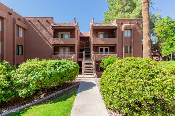 Front view of a multi-story apartment building with balconies and a central staircase.