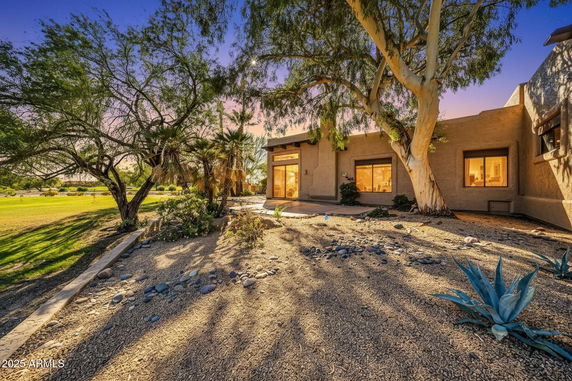 Front view of a single-story house with large windows and desert landscaping.