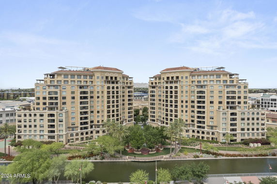 Front view of twin high-rise residential buildings with multiple balconies and a landscaped area in front.