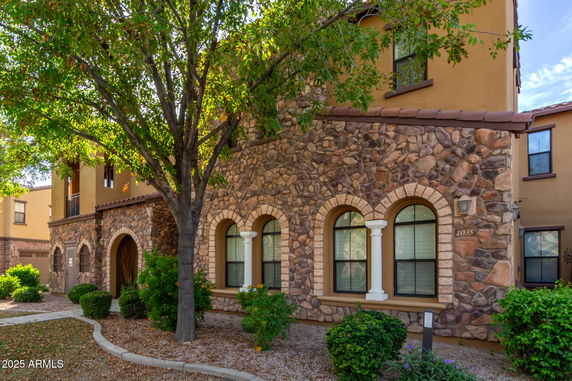 Front view of a multi-story house with stone facade and arched windows.