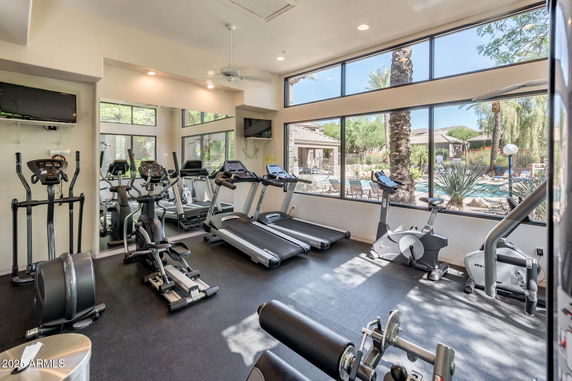 Interior view of a gym with exercise equipment and large windows overlooking an outdoor area.