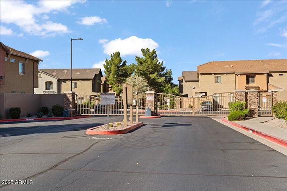 Front view of gated residential complex with townhouses and a paved road.