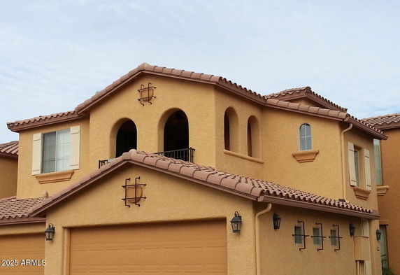 Front view of a two-story house with a tiled roof and arched windows.