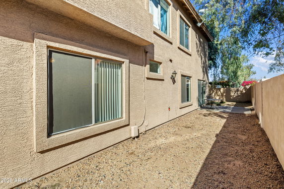 Side view of a two-story house with multiple windows and a narrow gravel path.