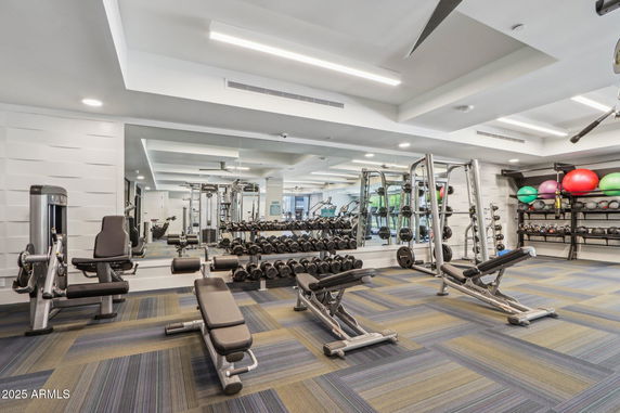 Interior view of a modern gym with workout equipment and mirrors.