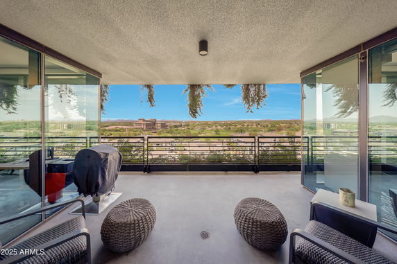 Panoramic view from a balcony overlooking a cityscape with buildings and distant mountains.
