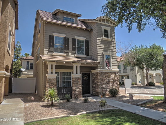Front view of a three-story house with stone accents and a front porch.