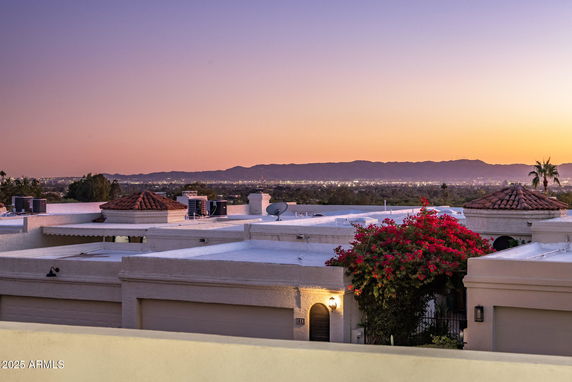 Wide-angle view of rooftops with a scenic mountain backdrop at sunset.