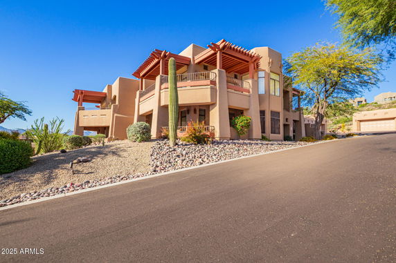 Front view of a multi-story house with architectural features and desert landscaping.