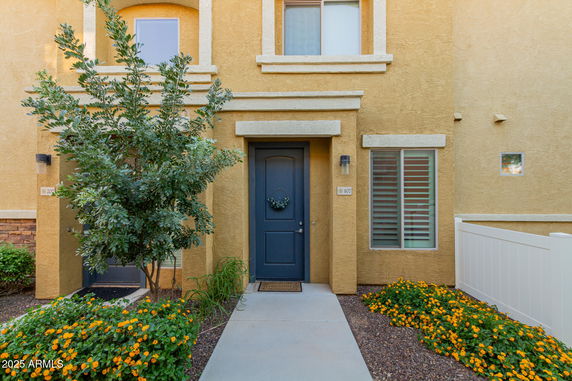 Front view of a two-story house with a blue door and yellow exterior.
