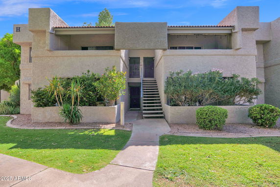 Front view of a two-story residential building with external stairs leading to the upper floor.