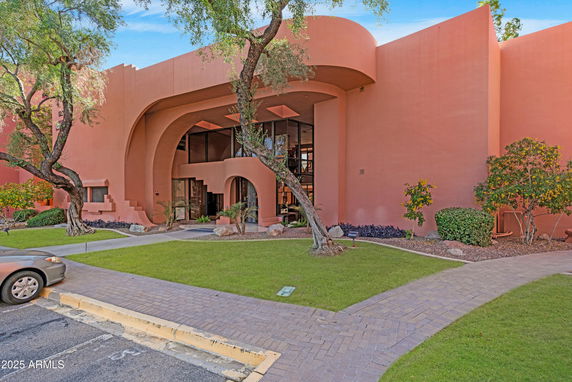 Front view of a modern two-story building with arched windows and pink exterior walls.