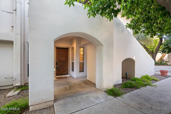 Front view of a house with an arched entrance and wooden door.