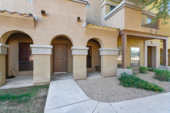 Front view of a building with arches and a brown door.
