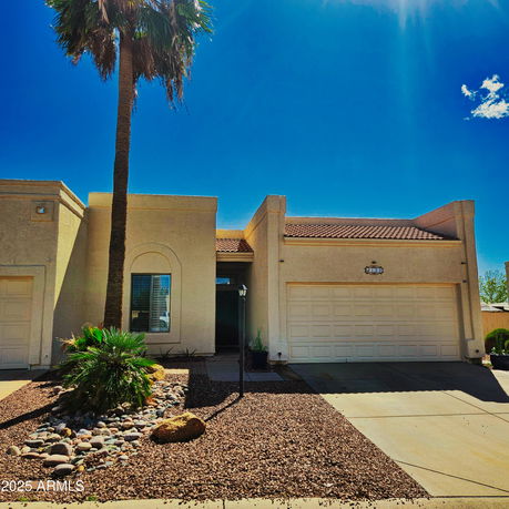 Front view of a single-story house with a double garage and a palm tree in the yard.