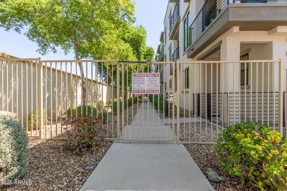 Front view of a multi-story building with metal railing and gated entrance.