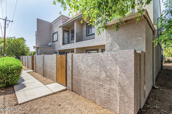 Front view of a two-story house with a textured wall and balcony.