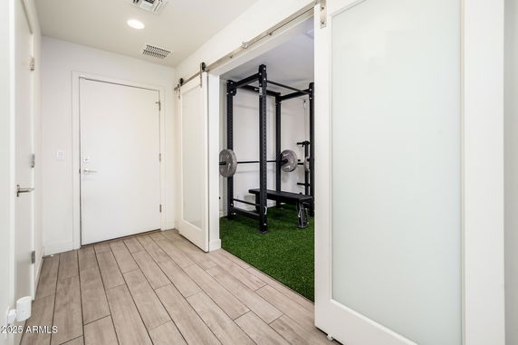 Indoor gym area with weightlifting equipment and wooden floor.