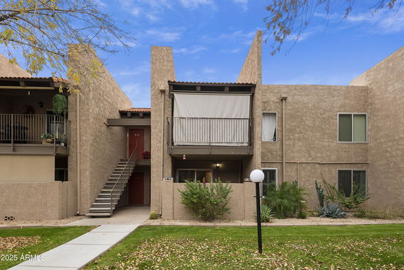 Front view of a two-story residential building with balconies and external staircase.