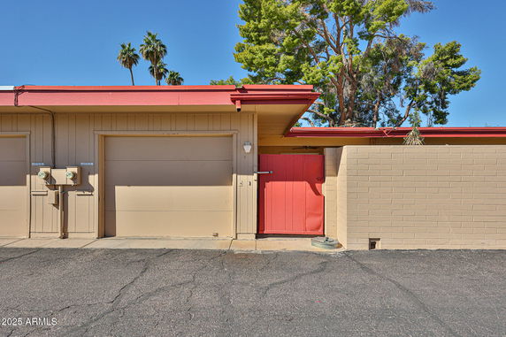Front view of a garage with a red door and beige walls.