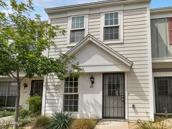 Front view of a two-story townhouse with white siding and barred windows.